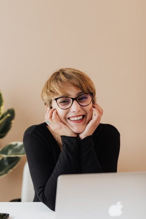 Cheerful woman smiling while sitting at table with laptop prwire